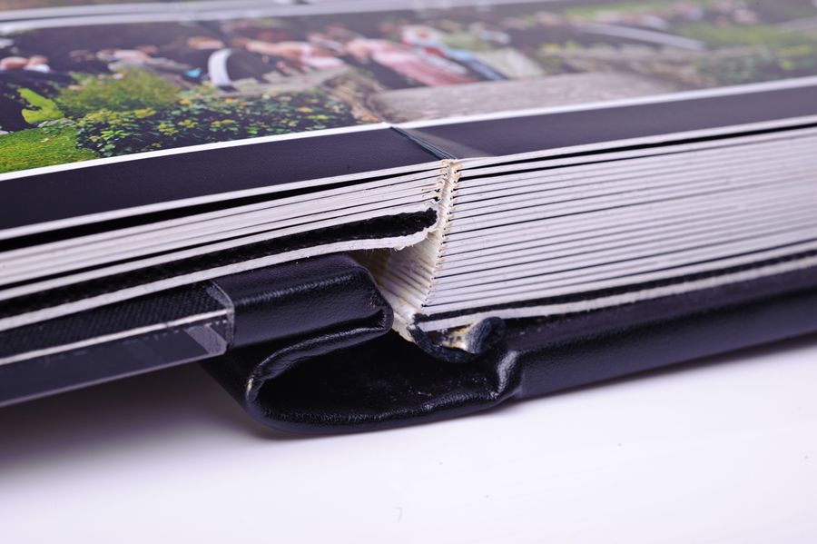 D3A_9236-copy | Weddings by Michael Close-up of a photo album with a bent spine and damaged binding, showing folded pages and worn cover edge.
