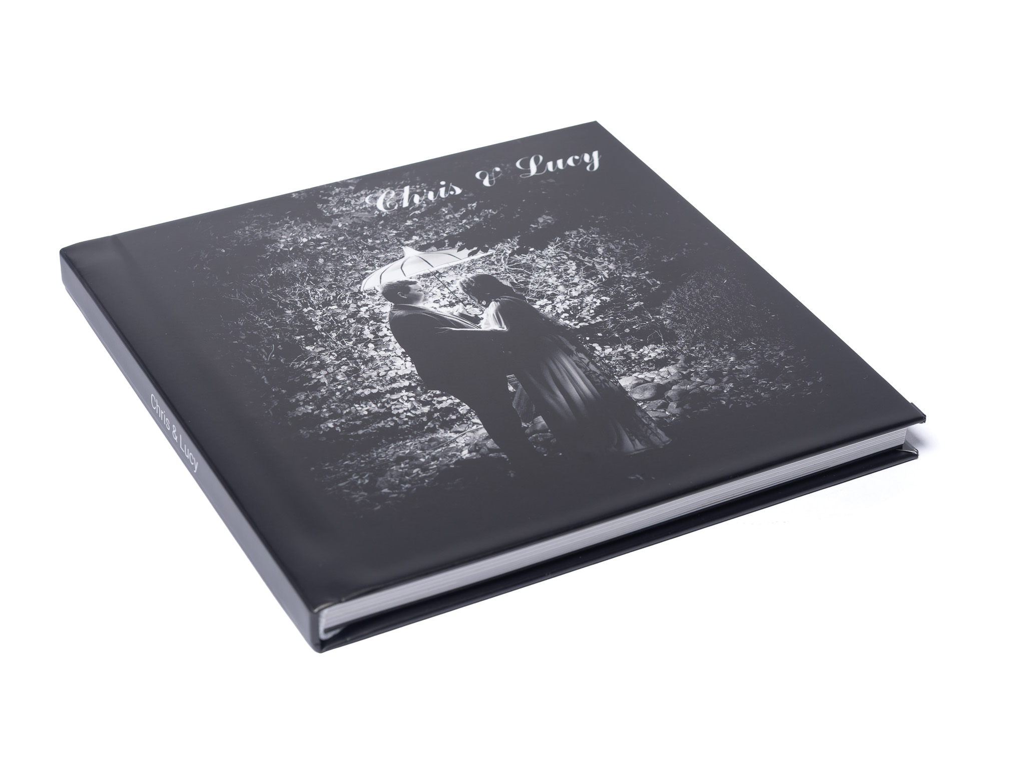 MemoryAlbum_01 | Weddings by Michael Hardcover photo book cover titled 'Chris & Lucy' with a couple under an umbrella in a forest scene (black and white).