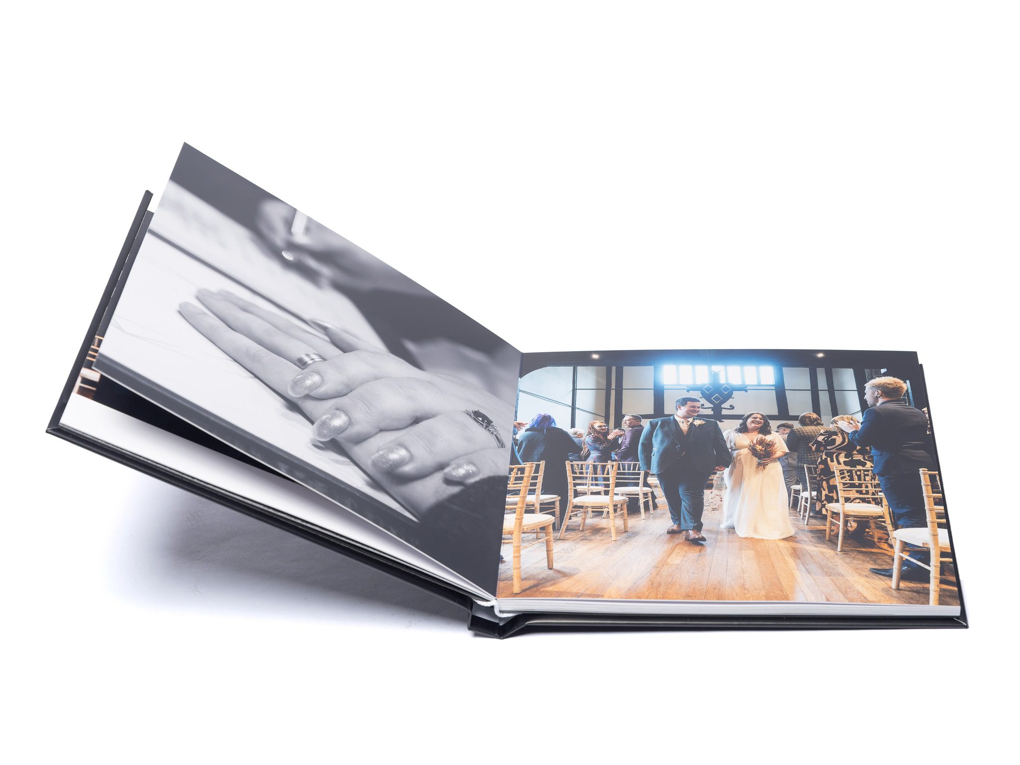 MemoryAlbum_02 | Weddings by Michael Open photo album displaying wedding photos, left page a close-up of clasped hands, right page guests at a ceremony in chairs.