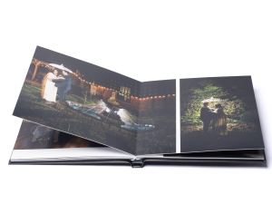 Open photo album displaying wedding photos of a couple embracing outdoors at night; string lights in the background.